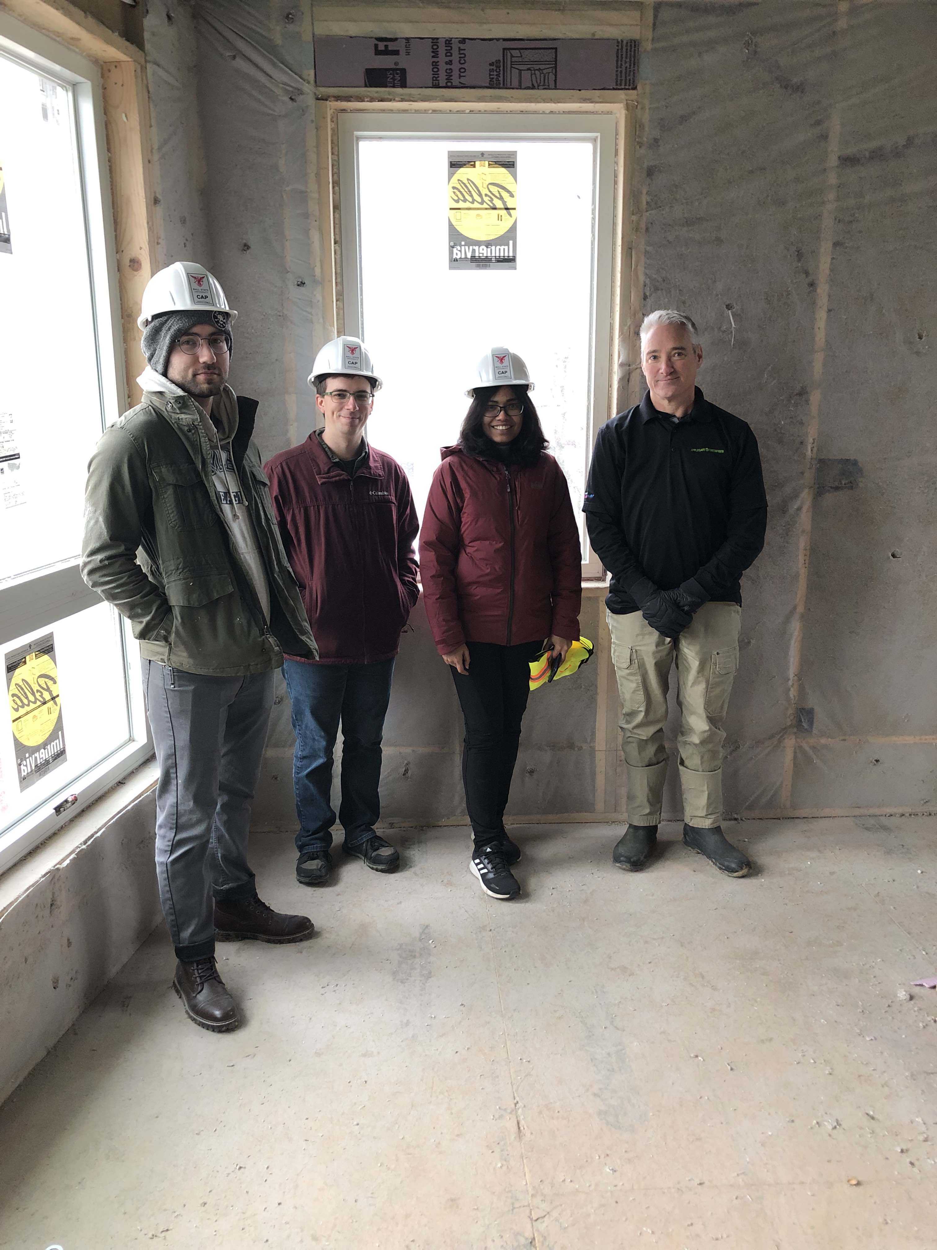 three ball state university students and a greenfiber sales rep stand inside an unfinished house 