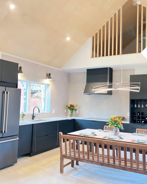 Interior of a white kitchen with dark blue cabinets and a cathedral ceiling